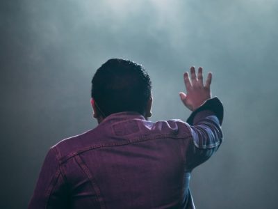 man in red jacket covering his face with his hands