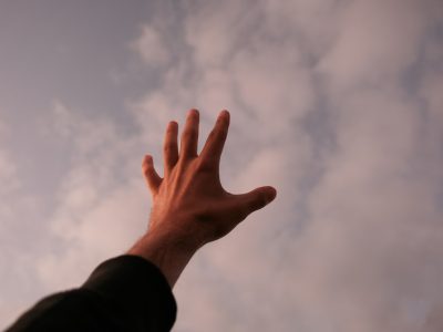 a person's hand reaching up into the sky