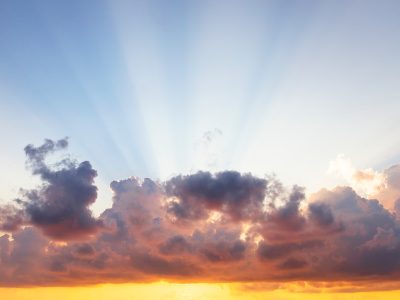 man raising his arms on sea under black clouds