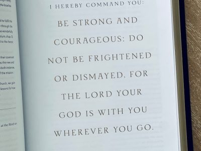 An open book on a wooden table with a pen