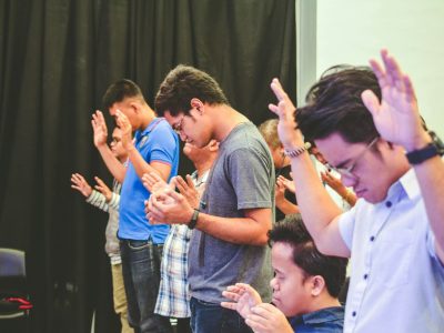people raising hands while closing their eyes inside room