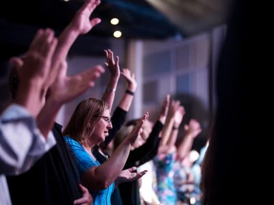 a group of people sitting in a room with their hands in the air