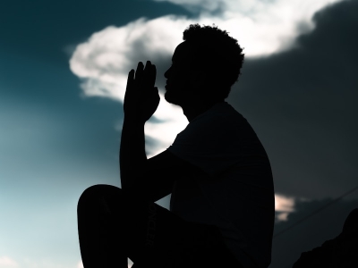 silhouette of man sitting on rock during daytime